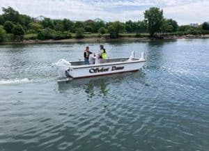 Fitzgerald Metalworks A small motorboat named "Silver Dawn" on a body of water with two people on board wearing safety vests.