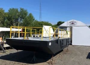 Fitzgerald Metalworks. A black barge with yellow railings on supports in front of a tent