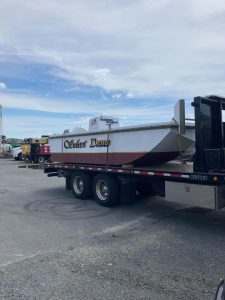 Fitzgerald Metal Works. The boat "Silver Dawn," a white and red painted boat is loaded onto a flatbed trailer, ready for transport.