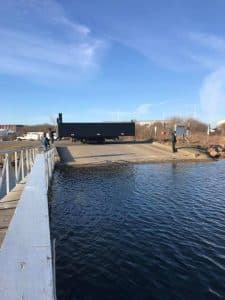 Fitzgerald Metal Works. Large black barge on trailer being brought down a ramp