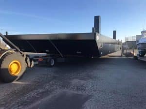 Fitzgerald Metal Works. A large black flat-bottomed barge being transported.