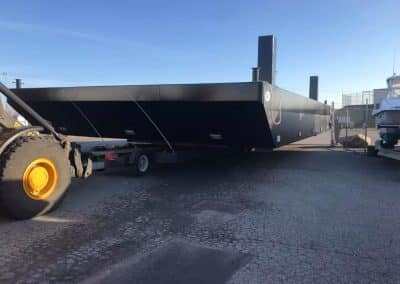 Fitzgerald Metal Works. A large black flat-bottomed barge being transported.