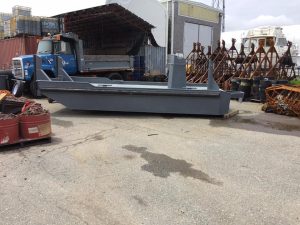 Fitzgerald Metalworks. A small grey workboat or utility barge placed on the ground in an industrial yard.