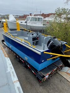 Fitzgerald Metalworks. Blue barge work boat on trailer.