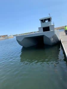 Fitzgerald Metal Works. Grey barge in water attached to a dock.