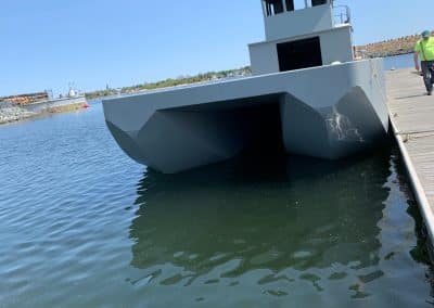 Fitzgerald Metal Works. Grey barge in water attached to a dock.