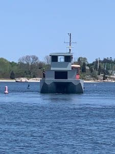 Fitzgerald Metal Works. Large grey barge in water being pulled by a red tug boat