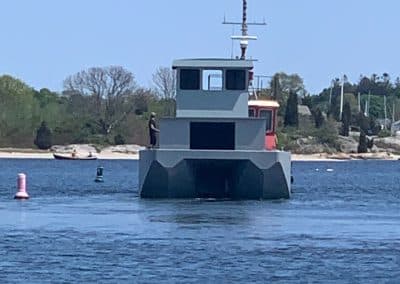 Fitzgerald Metal Works. Large grey barge in water being pulled by a red tug boat