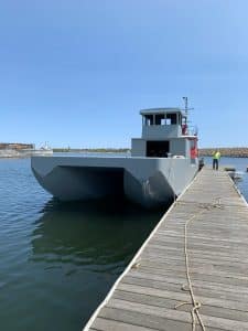 Fitzgerald Metal Works. Large grey barge in water next to dock.