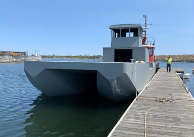 Fitzgerald Metal Works. Large grey barge in water next to dock.