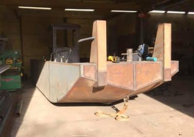 Fitzgerald Metal Works. A metal boat hull inside a workshop.