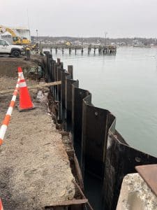 Fitzgerald Metal Works. Marine Construction Site. Black metal sheets next to water and orange traffic cones in background