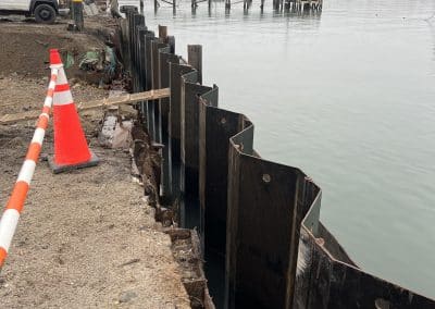 Fitzgerald Metal Works. Marine Construction Site. Black metal sheets next to water and orange traffic cones in background