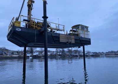 Fitzgerald Metal Works. A barge elevated above the water on stilts on a overcast day