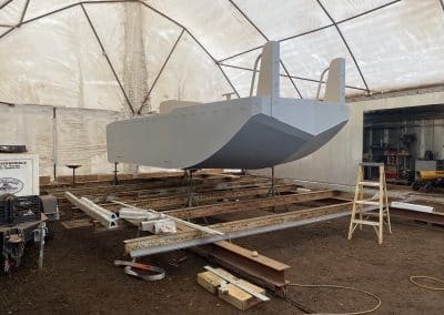 Fitzgerald Metal Works. A boat under construction inside a large, enclosed tent or workshop.