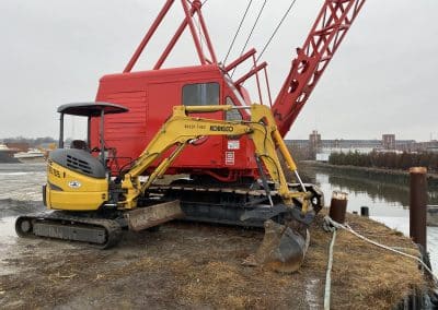 Fitzgerald Metalworks. Red crane and yellow tractor by a body of water.