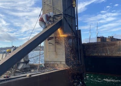 Fitzgerald Metalworks. A marine fabrication professional is welding on a barge in the water