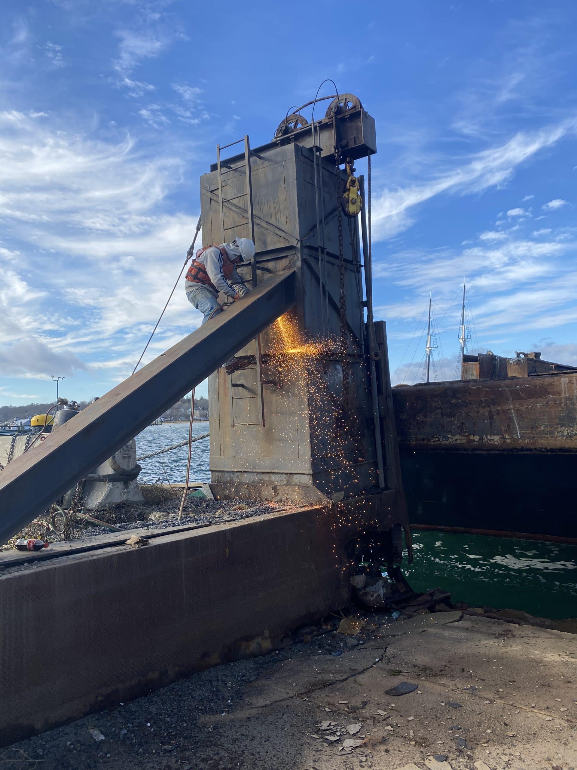 Fitzgerald Metalworks. A marine fabrication professional is welding on a barge in the water