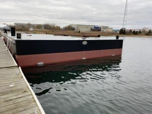 Fitzgerald Metalworks. Barge boat in water tied to dock.