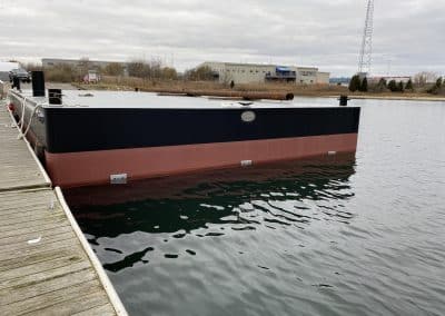 Fitzgerald Metalworks. Barge boat in water tied to dock.