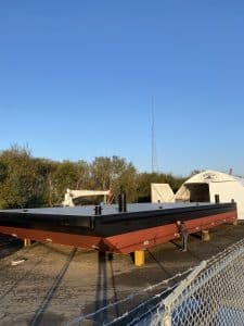 Fitzgerald Metalworks. Black and red barge boat on yellow and brown wooden supports.