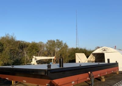 Fitzgerald Metalworks. Black and red barge boat on yellow and brown wooden supports.