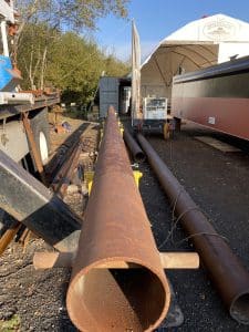 Fitzgerald Metalworks. Rusty brown Pipe in the center of image surrounded by other rusty pipes and a truck. Fitzgerald Metalworks.