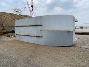 Fitzgerald Metalworks. A barge vessel, lying on its side in an outdoor boatyard.