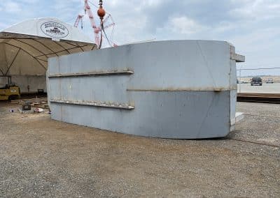 Fitzgerald Metalworks. A barge vessel, lying on its side in an outdoor boatyard.