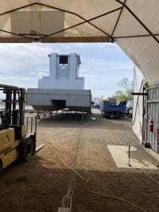 Fitzgerald Metalworks. View from inside a workshop or storage tent, looking out towards an outdoor work area where there there are several vessels being constructed.