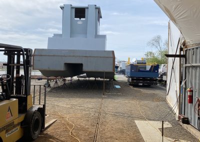 Fitzgerald Metalworks. View from inside a workshop or storage tent, looking out towards an outdoor work area where there there are several vessels being constructed.