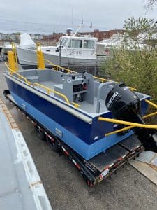 Fitzgerald Metalworks. A small blue and yellow utility barge boat on a trailer, ready for transport.