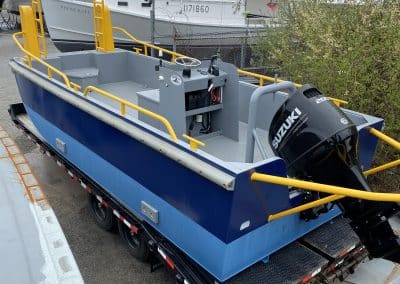 Fitzgerald Metalworks. A small blue and yellow utility barge boat on a trailer, ready for transport.