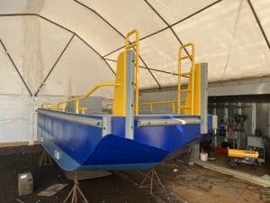 Fitzgerald Metalworks. The rear view of a barge, likely under construction or maintenance, in a covered workshop area in a tent