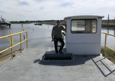 Fitzgerald Metalworks. A man standing on the deck of a barge, leaning against a white cabin.