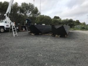 Fitzgerald Metal Works. Two large, newly constructed black barge hulls placed on wooden supports