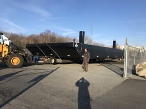 Fitzgerald Metal Works. A large black barge being moved on a trailer.