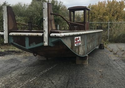 Fitzgerald Metal Works. Old, rusted metal barge boat hull sitting on supports