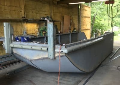 Fitzgerald Metal Works. Front view of metal boat hull in process of being constructed in workshop